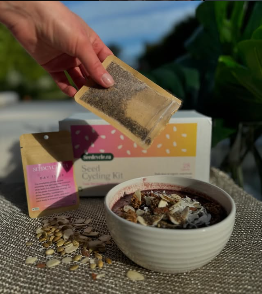 Organic seed blend from the Seed Cycle Kit being poured into a bowl of yogurt – simple daily recipe to support natural hormone balance, reduce PMS, and boost women’s wellness